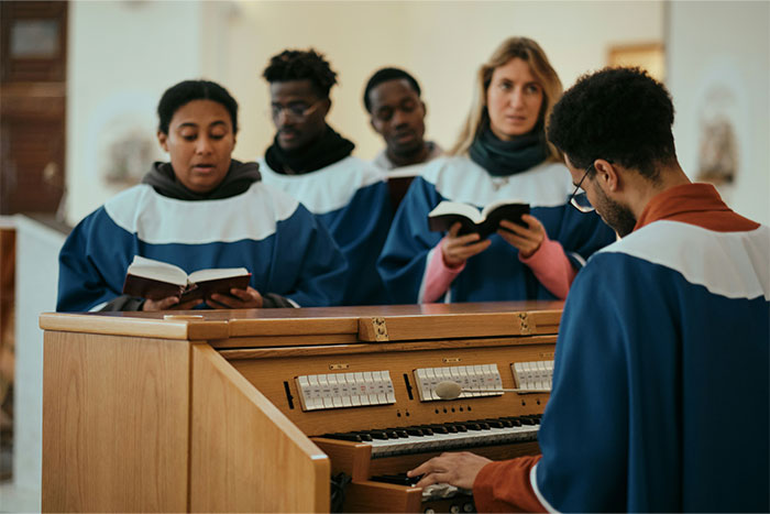Choir wearing blue robes sings beside an organist, capturing a moment of crazy coincidences during a practice session.