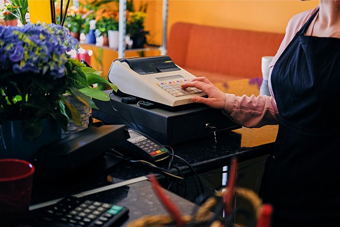 Person using an old cash register in a flower shop, illustrating crazy coincidences in retail settings.