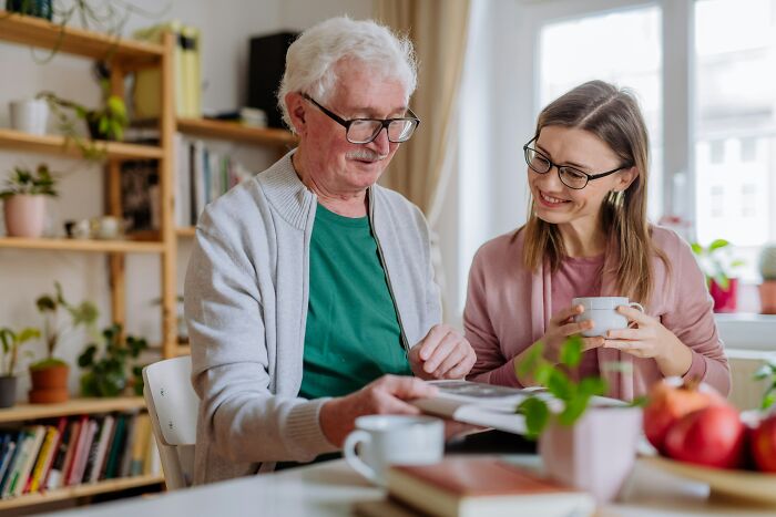Older man and woman in a cozy room, discussing a book, illustrating partnership during hard times.
