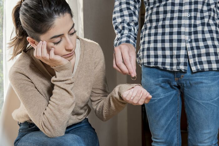 A woman appears concerned while a man hands her a ring, symbolizing stuck hard times in relationships.