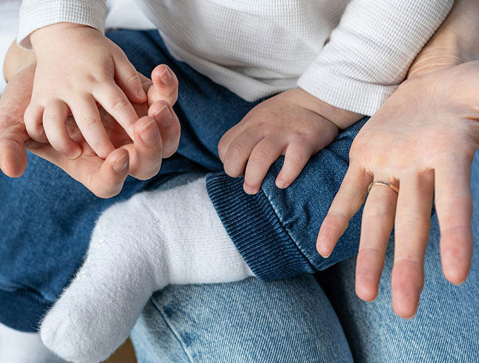 Hands of an adult and a baby, symbolizing babysitting and family care. Hands of an adult and a baby, symbolizing babysitting and family care.