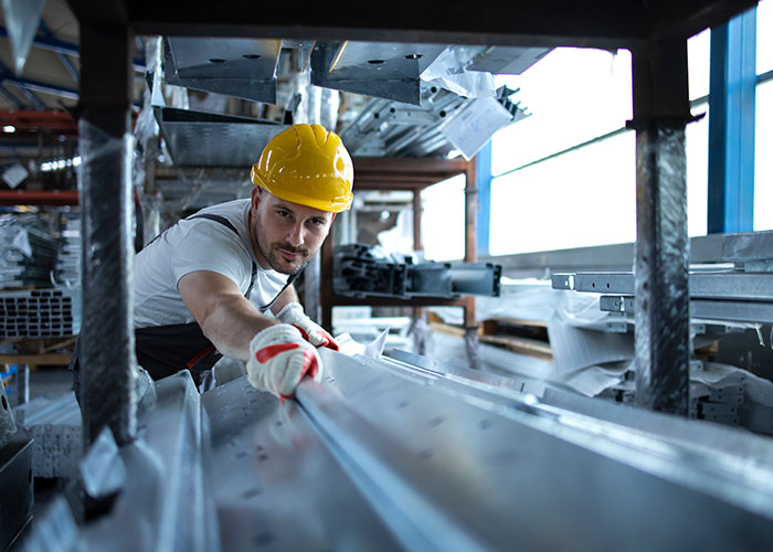Worker in a hard hat reaching for a metal beam, representing people doing unsafe tasks despite warnings.