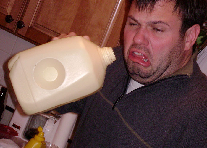 Man grimacing while pouring from a milk jug, highlighting stupid things people did against advice.