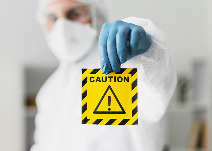 Person in protective gear holding a caution sign, highlighting stupid actions despite warnings.
