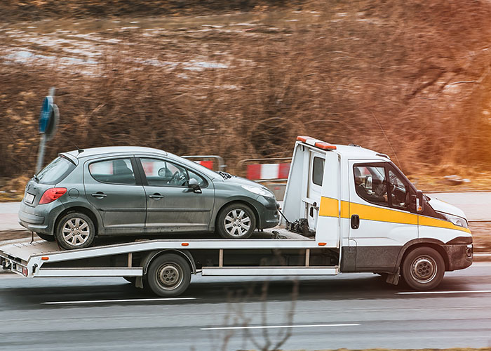 Tow truck transporting a car, illustrating one of many stupid things people did despite warnings.