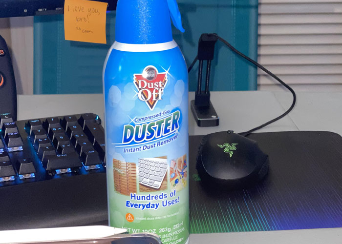 A can of duster on a desk beside a keyboard and mouse, representing actions people were advised against.