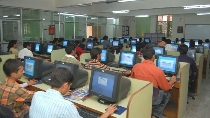 People in a computer lab exploiting loopholes, busy working on desktop computers.