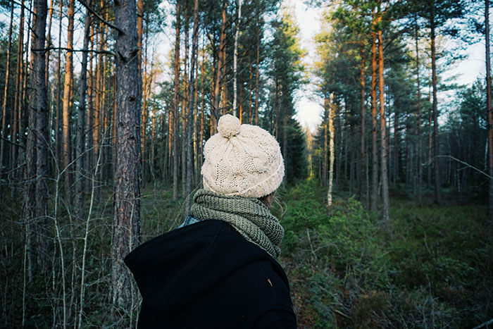 Person in warm clothing in a forest setting, possibly discovering surprising facts in nature.
