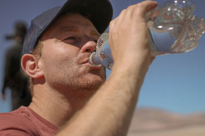 Man in a red shirt and cap drinking water, highlighting lifesaver facts for hydration.