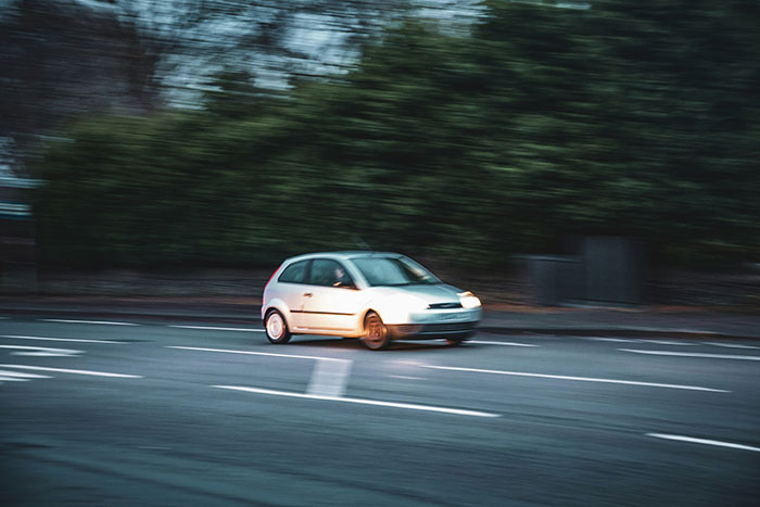 A white car speeding on a road, showcasing surprising lifesaving driving skills.