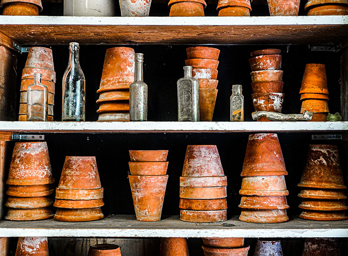 Old terracotta pots and glass bottles on shelves, showcasing lifesaver tips for unexpected uses.