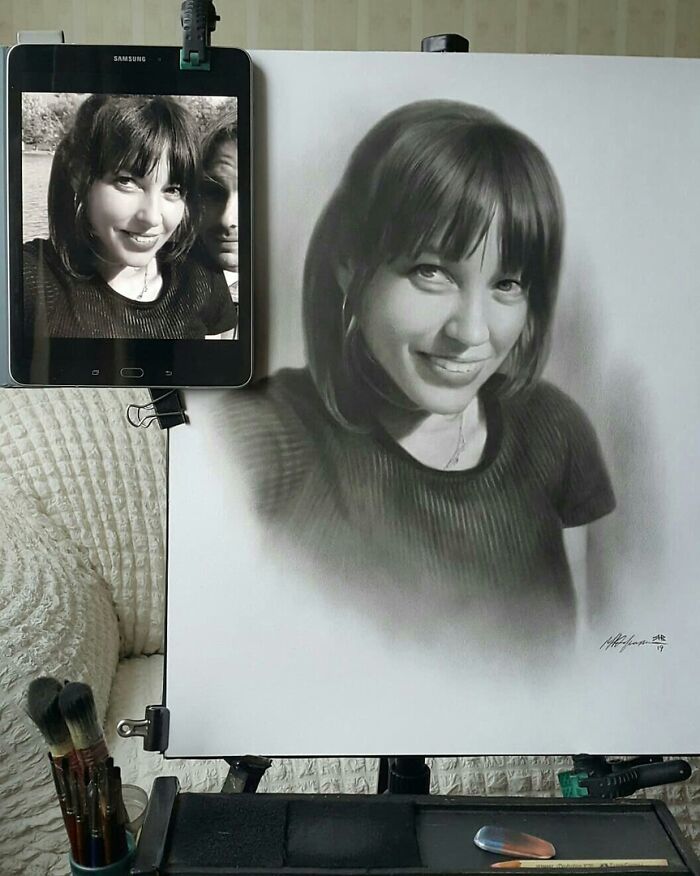 Pencil drawing of a woman beside her photo on a tablet, showcasing hyper-realistic portrait art.
