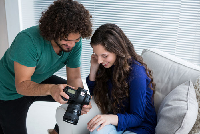 Woman with camera reviews engagement photos, focus on friendship dynamic.