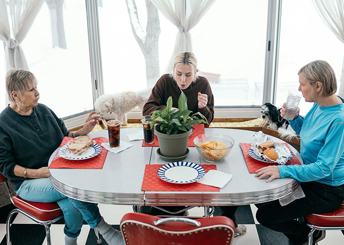 Three women sitting around a dining table with lunch, discussing grandpa's will and family affairs. Three women sitting around a dining table with lunch, discussing grandpa's will and family affairs.