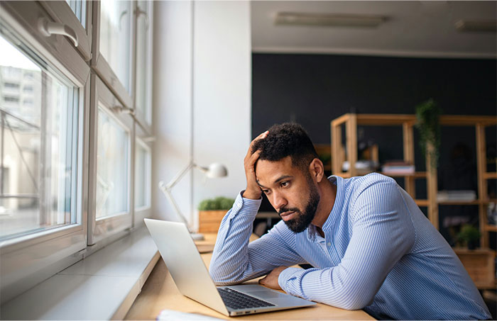 Teacher looking concerned while sitting at a desk with a laptop, reflecting on authority in the classroom.
