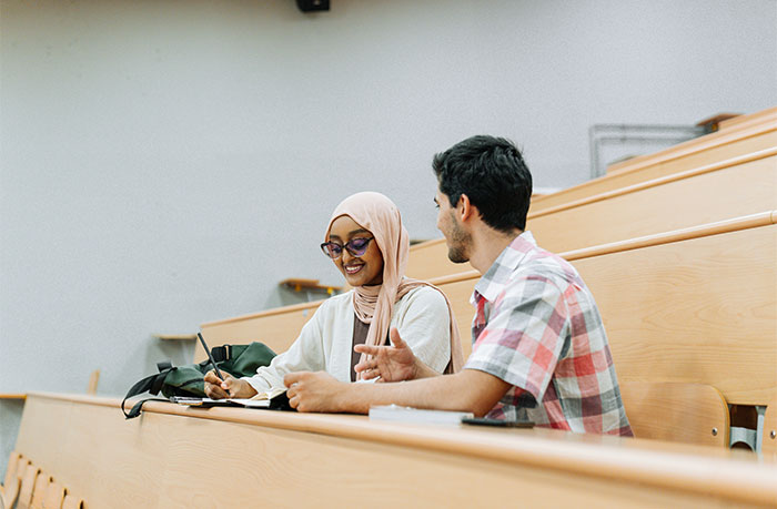Teacher and student in a lecture hall discussing class notes, fostering a positive learning environment.