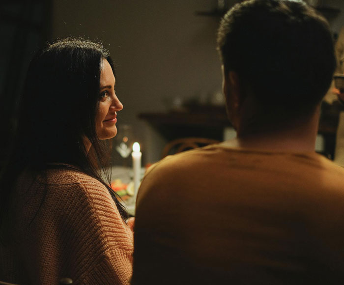 Woman and man at a candlelit engagement dinner, creating an intimate atmosphere.
