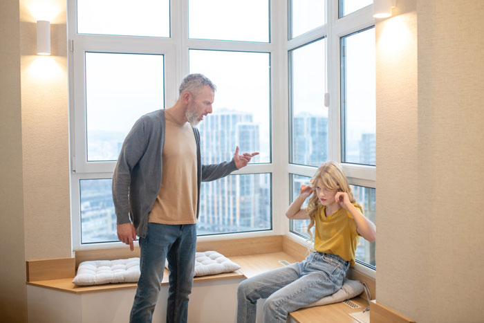 Dad and child in a tense moment near a window during an engagement dinner discussion.