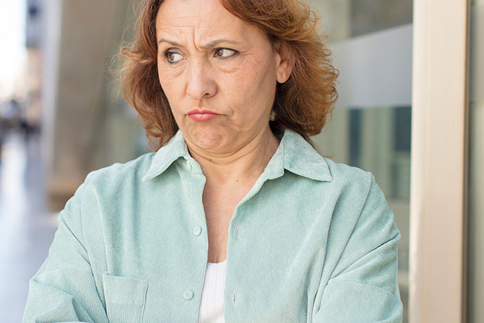 Middle-aged woman with crossed arms looking displeased, illustrating aunt starts drama in niece&rsquo;s life concept.