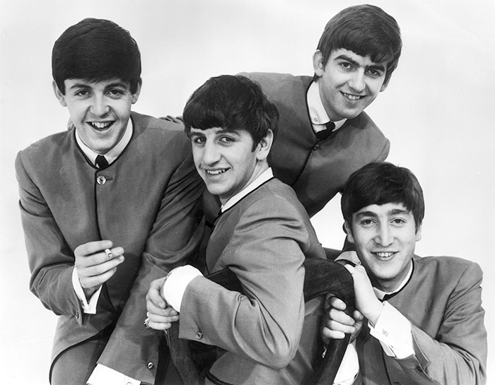 The Beatles posed together, smiling in classic suits, related to casting controversy.