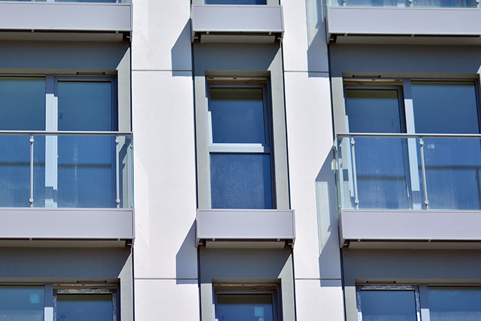 European building facade with numerous glass balconies, reflecting architectural style.