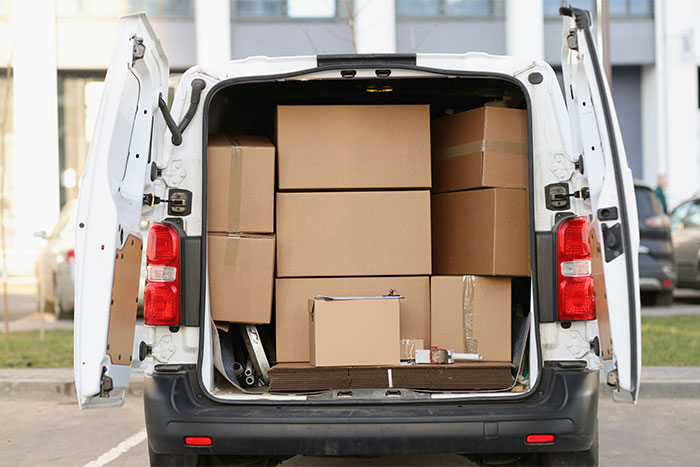 Open van filled with cardboard boxes at loading area, illustrating money saving tips for cost-effective moving.