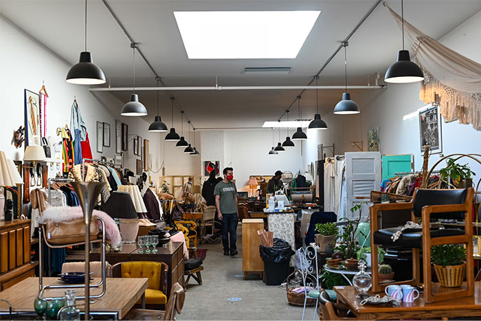 People browsing a thrift store filled with vintage furniture, illustrating money-saving tips from the Great Recession.