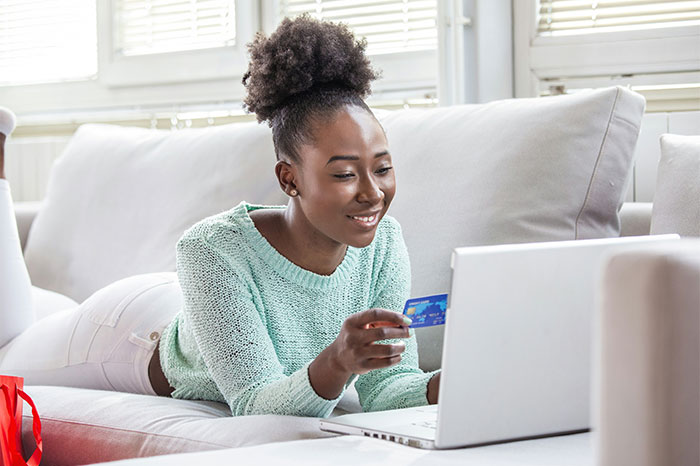 Woman using a laptop with a credit card, reflecting money-saving strategies from the Great Recession era.