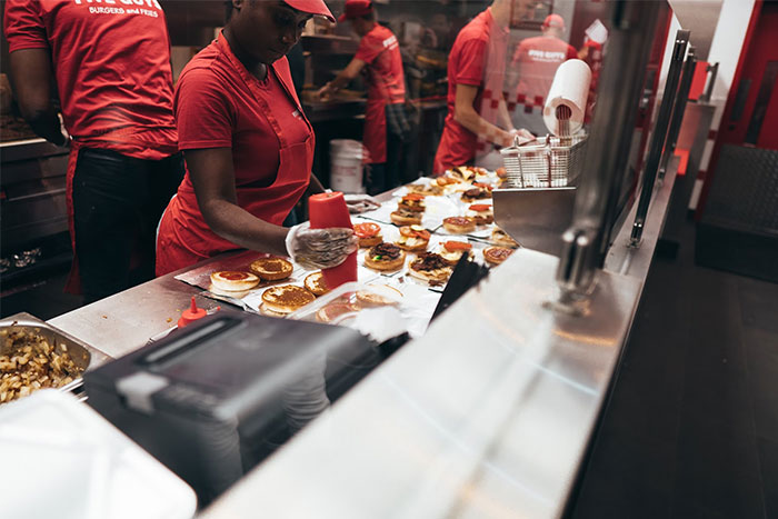 Workers in a fast-food kitchen preparing burgers, illustrating money-saving tips from the Great Recession era.
