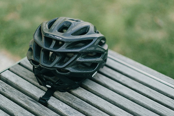 A black motorcycle helmet resting on a wooden outdoor bench.