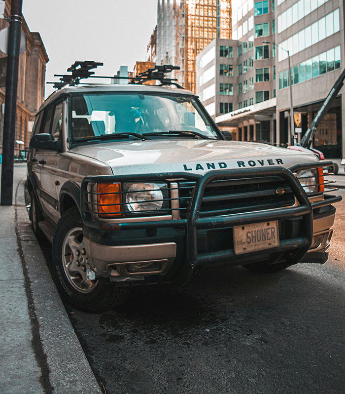 Land Rover parked on city street, highlighting the vehicle's rugged design.
