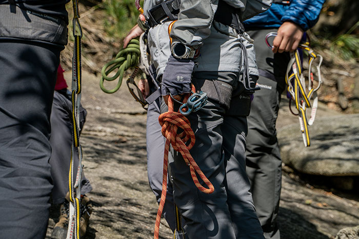 Rock climbers on a mountain path, harnesses equipped, focusing on ascent safety, no motorcycle helmet visible.