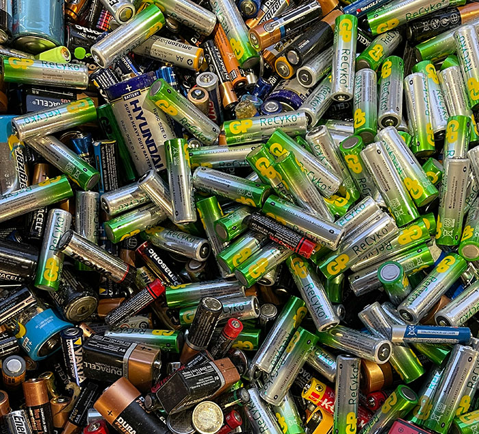 A pile of used batteries with various brands and colors, highlighting recycling needs and safety similar to motorcycle helmet care.