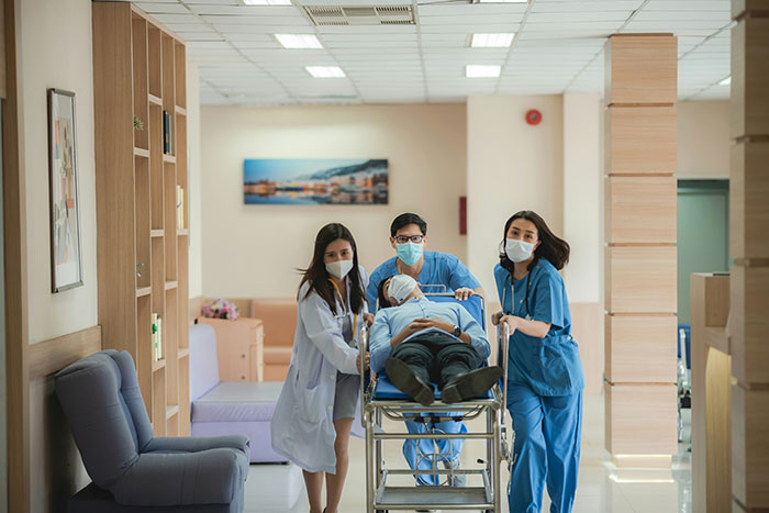Medical team in hospital hallway, wearing masks, transporting a patient on a stretcher to ensure safety and care.