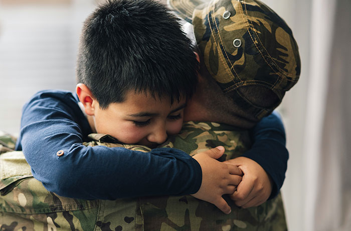 Child embracing a person in camouflage, a life-changing moment for safety and security.