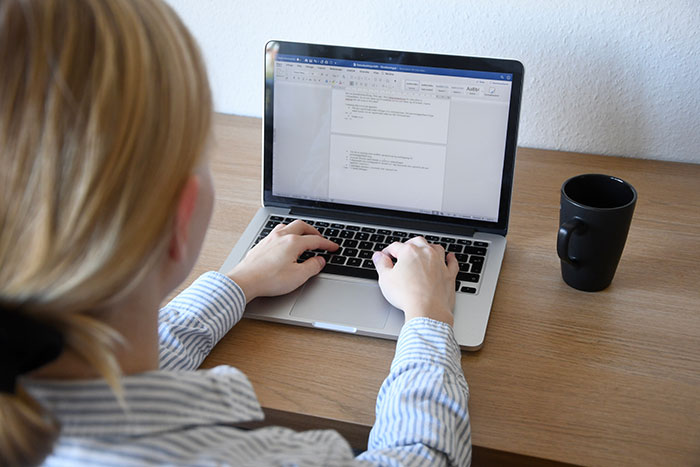 Person at desk using a laptop for writing, illustrating life-changing safety habits.