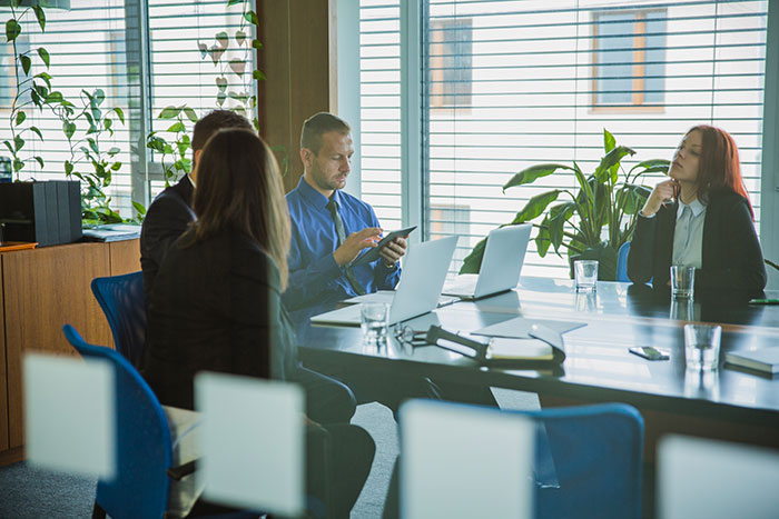Group in a conference room, discussing changes for safety, with laptops and notepads in a professional setting.