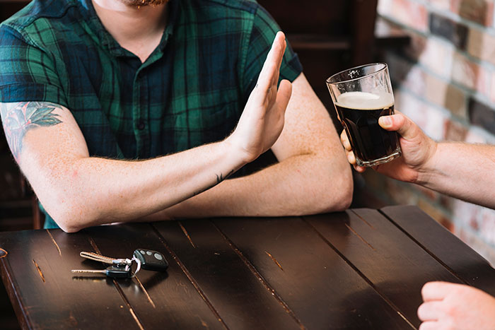 Person declining a drink, keys on table, illustrating a safe choice changing lives.