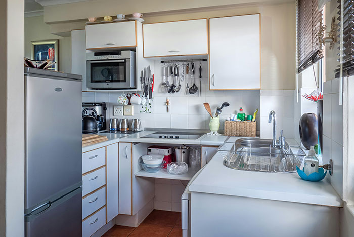 Clean kitchen with modern appliances and organized utensils, highlighting areas to clean before hosting guests.