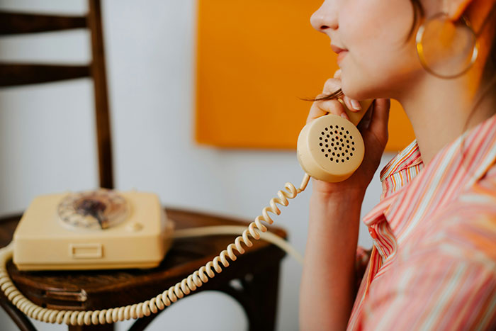 Young woman using a vintage rotary phone, highlighting how normal outdated technology once was.