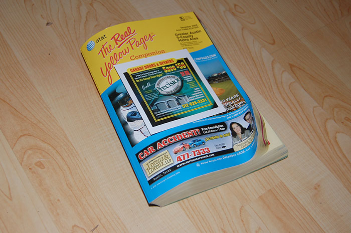 Real Yellow Pages book on a wooden floor, showcasing advertising and listings, once a normal household item.