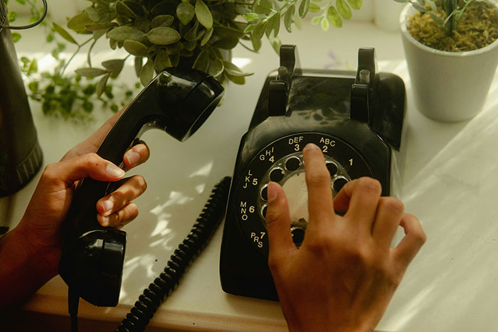 A person dialing a vintage rotary phone, a nostalgic item that was once normal but might shock people in 2025.