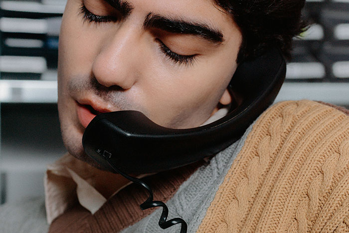 Person using a landline phone, reminiscent of a once-normal communication method.