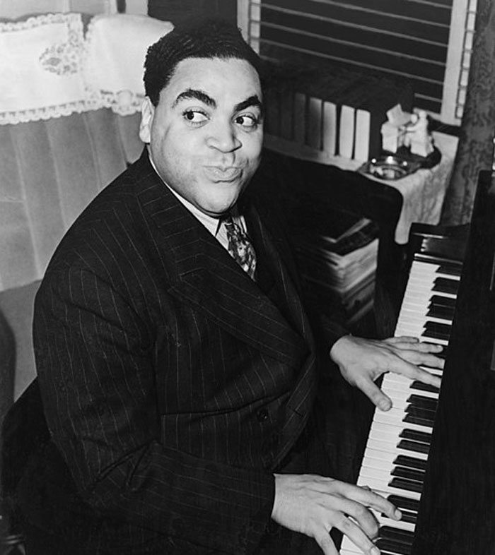 Person playing piano with a playful expression, captured in a classic black and white photo.