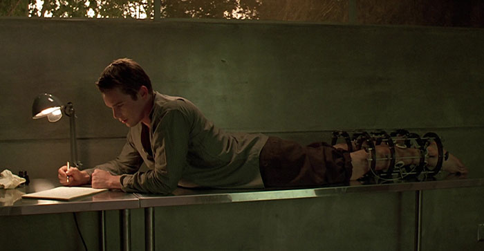 A person writing on a desk, legs in braces, under a lamp, symbolizing fun facts discovery.