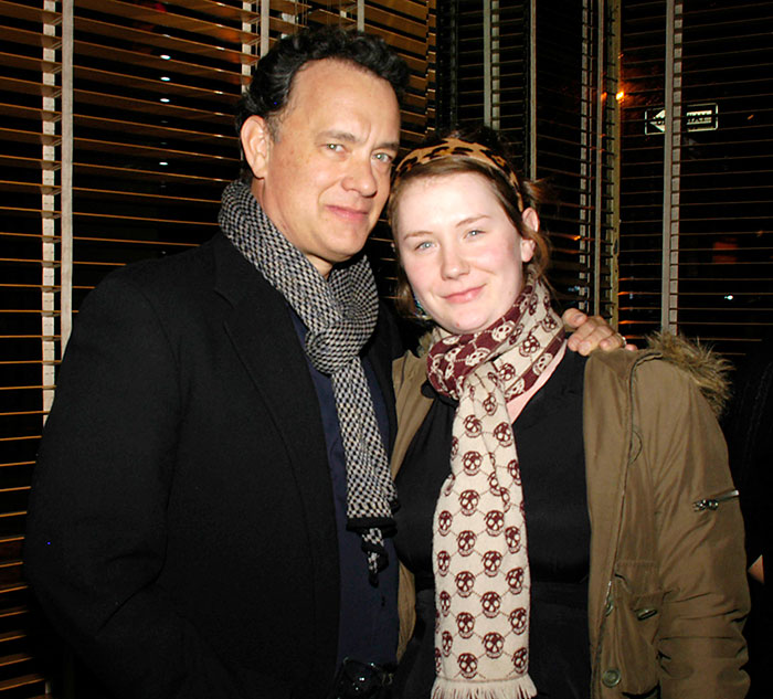 Father and daughter smiling together, dressed warmly with scarves, indoors.
