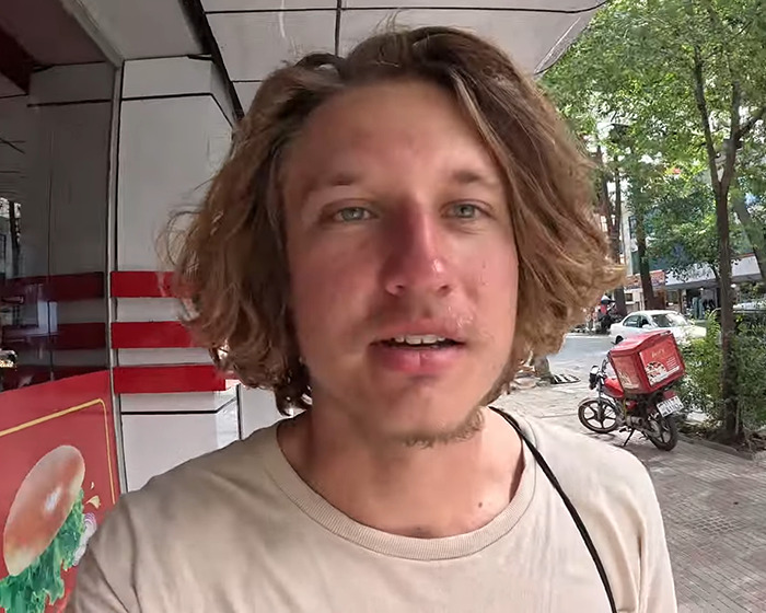 YouTuber outdoors on the street, wearing a beige shirt, related to isolated tribe stunt news.