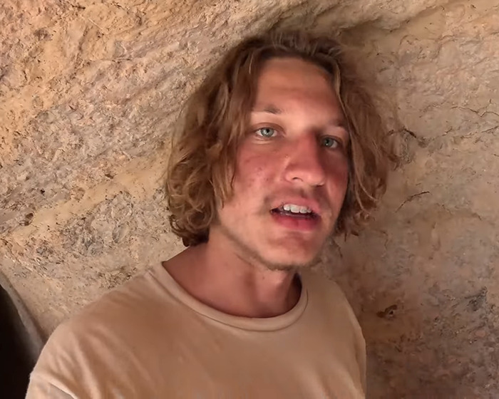 YouTuber posing in front of a rocky background, involved in isolated tribe Diet Coke incident.