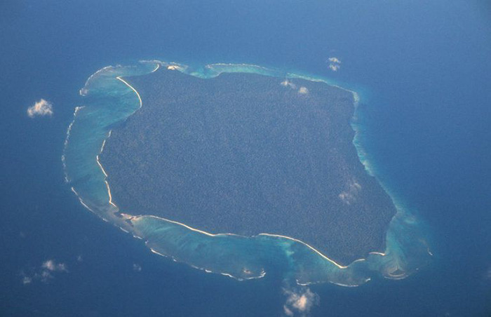 Aerial view of an isolated island surrounded by blue ocean, related to YouTuber facing jail for risking tribe's extinction.