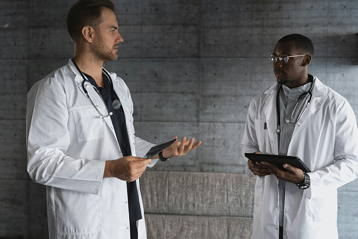 Two male doctors in white coats discussing medical information in a clinical setting about wife coming out as trans. Two male doctors in white coats discussing medical information in a clinical setting about wife coming out as trans.